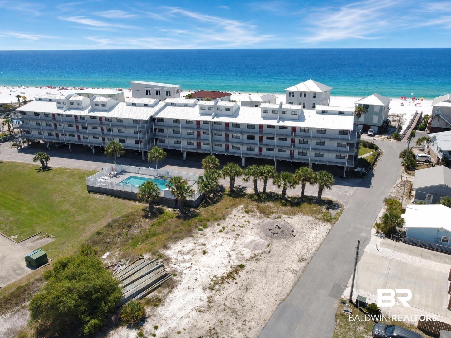 Image 1: Beachfront condominium building featuring multiple levels of balconies, an outdoor swimming pool, and a row of palm trees