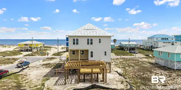 Image 3: New construction home featuring a light-colored exterior, multiple windows, and a prominent deck structure