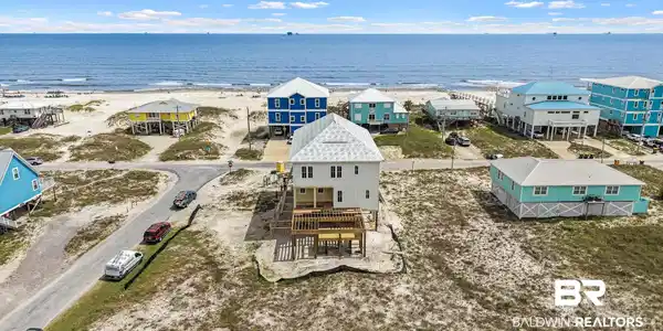 Image 4: Elevated coastal residence featuring white siding and a light-colored roof
