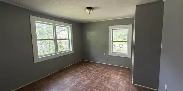 Image 4: Interior room featuring light gray walls and wood-finish flooring