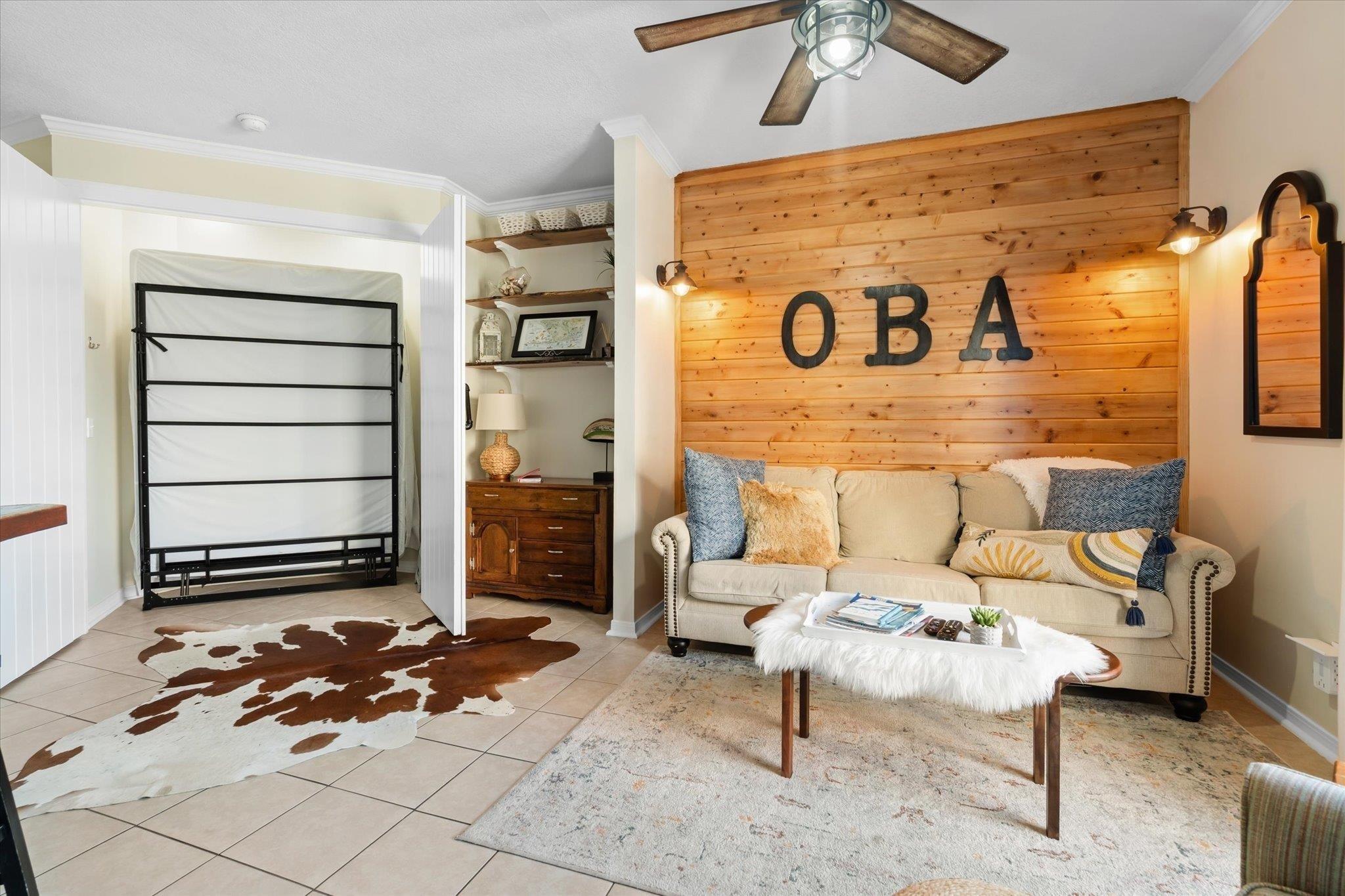 Image 4: Living room featuring ceiling fan, wooden walls, tile patterned flooring, and ornamental molding