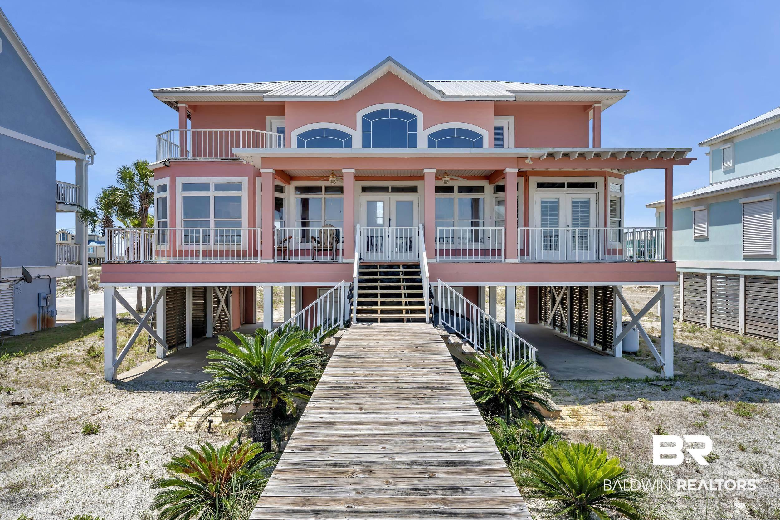 Image 3: Elevated residential structure featuring a prominent second-story balcony with white railings, multiple sets of double doors, and a metal roof