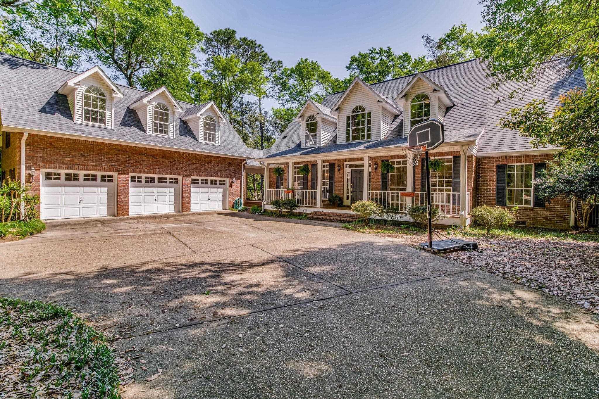 Image 1: Cape cod house featuring driveway, an attached garage, a porch, and brick siding