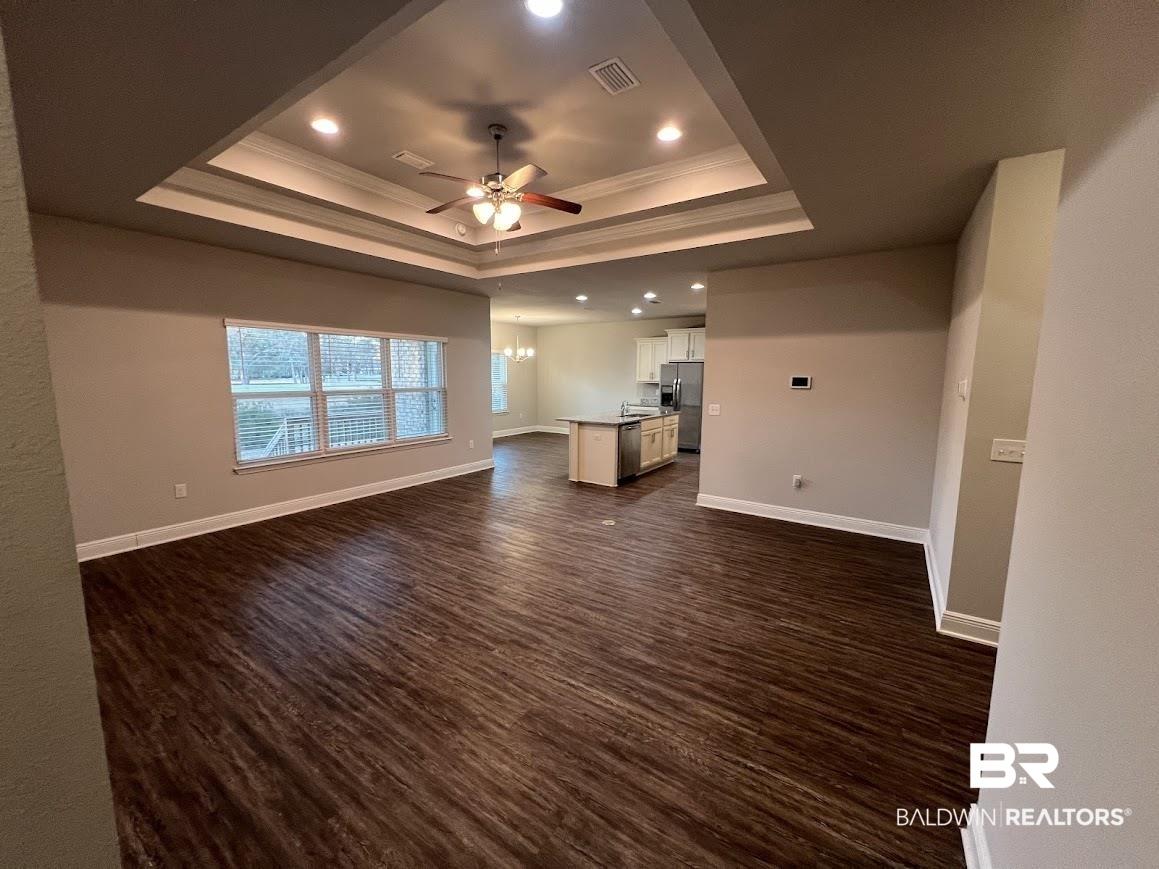 Image 3: Unfurnished living room featuring ornamental molding, a ceiling fan, dark wood-style floors, and hanging lights