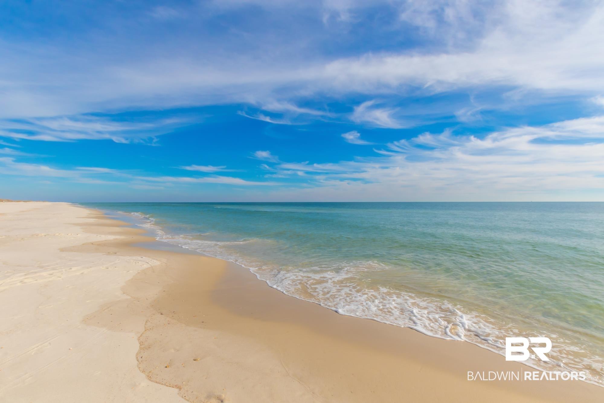 Image 2: Expansive sandy beach with calm ocean waters and a clear blue sky