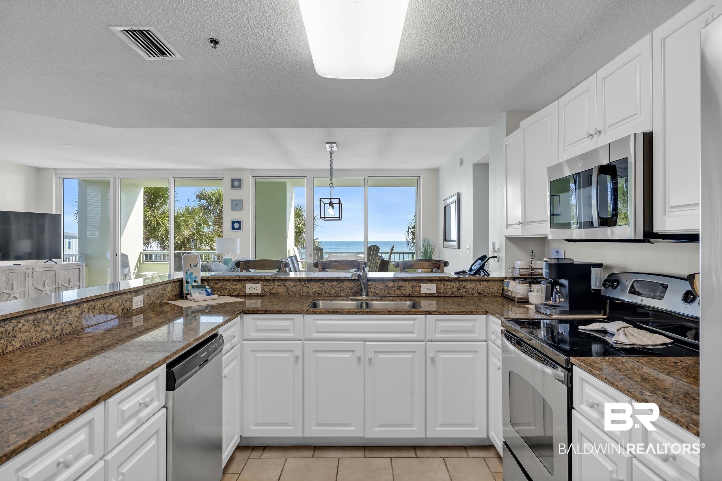 Image 3: Kitchen featuring stainless steel appliances, white cabinets, healthy amount of natural light, dark stone counters, and a textured ceiling