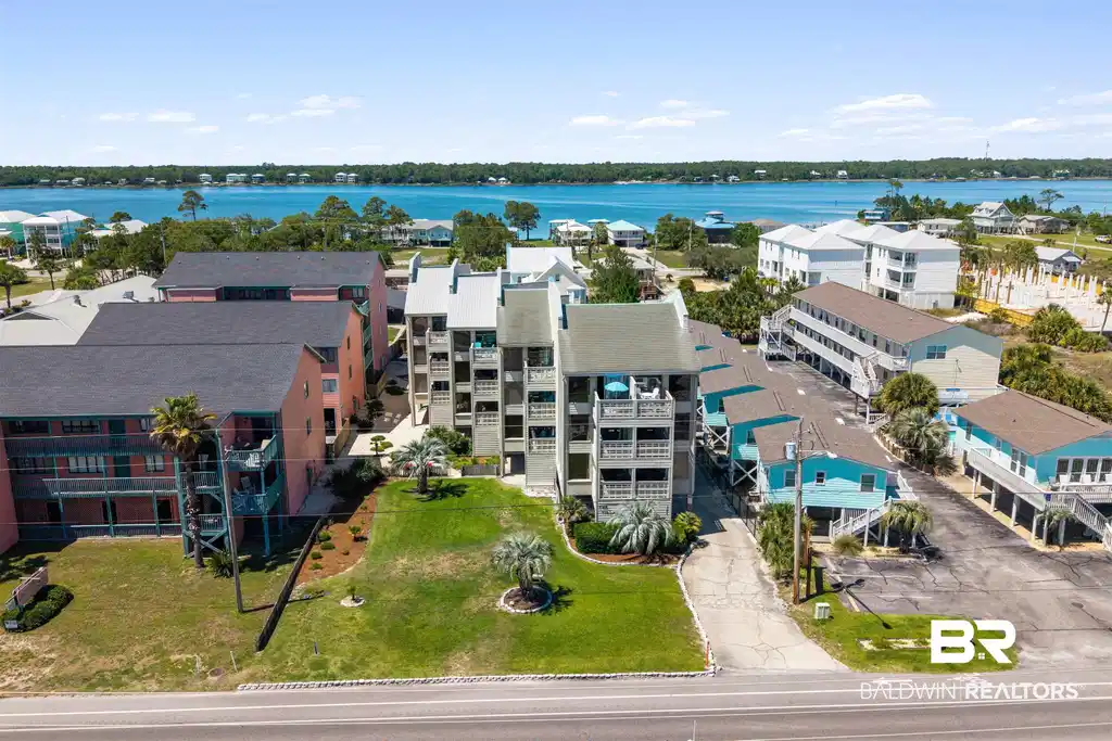 Image 1: Multi-story coastal residential property featuring multiple balconies, mature palm trees, and a manicured lawn