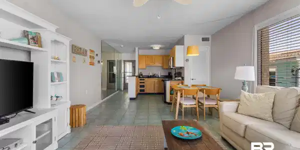 Image 3: Open-concept living area with tile flooring throughout, featuring a built-in media console, ceiling fan with integrated lighting, and a dining area with pendant lighting