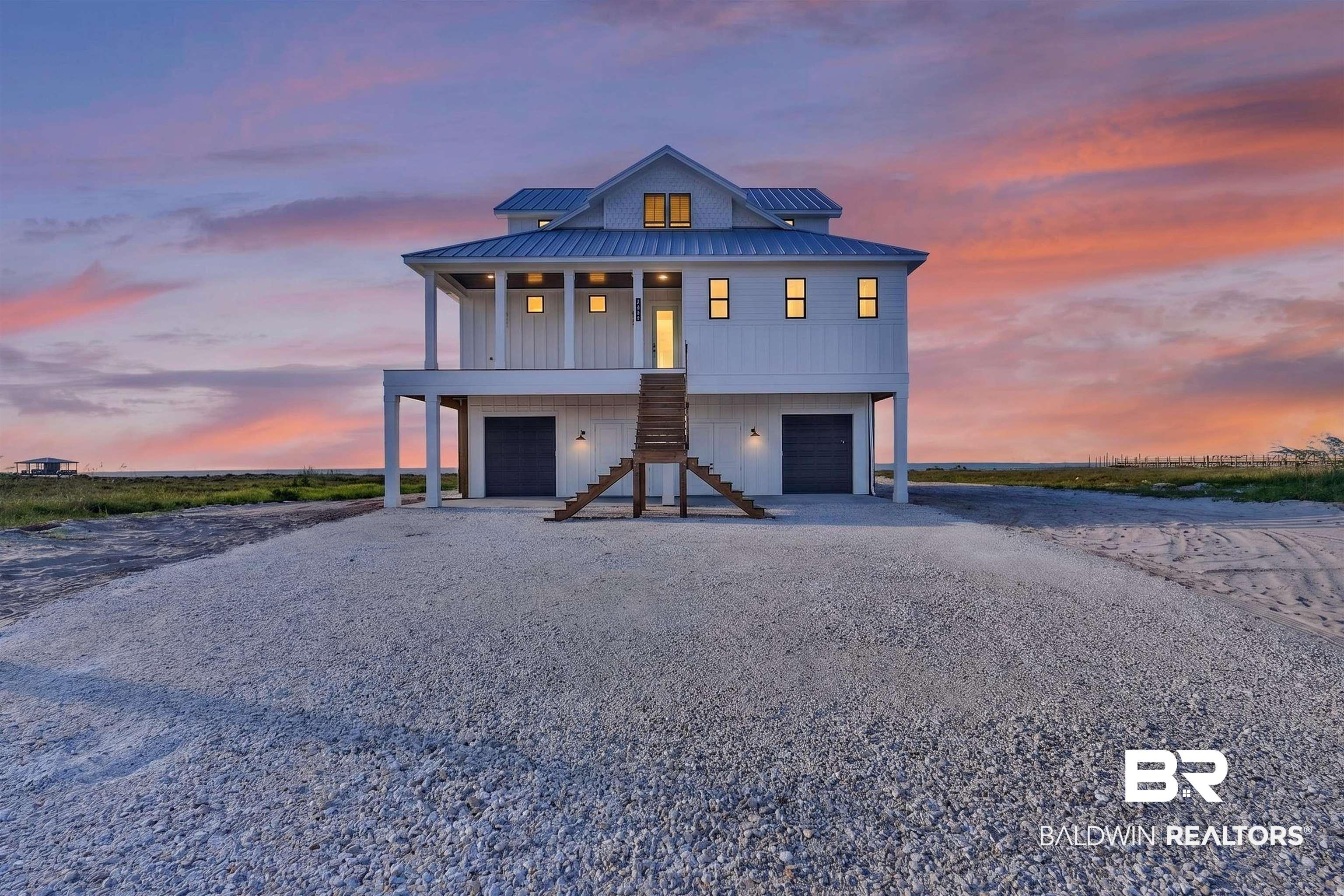 Image 1: Elevated coastal-style residence featuring a white vertical siding exterior and a blue metal roof