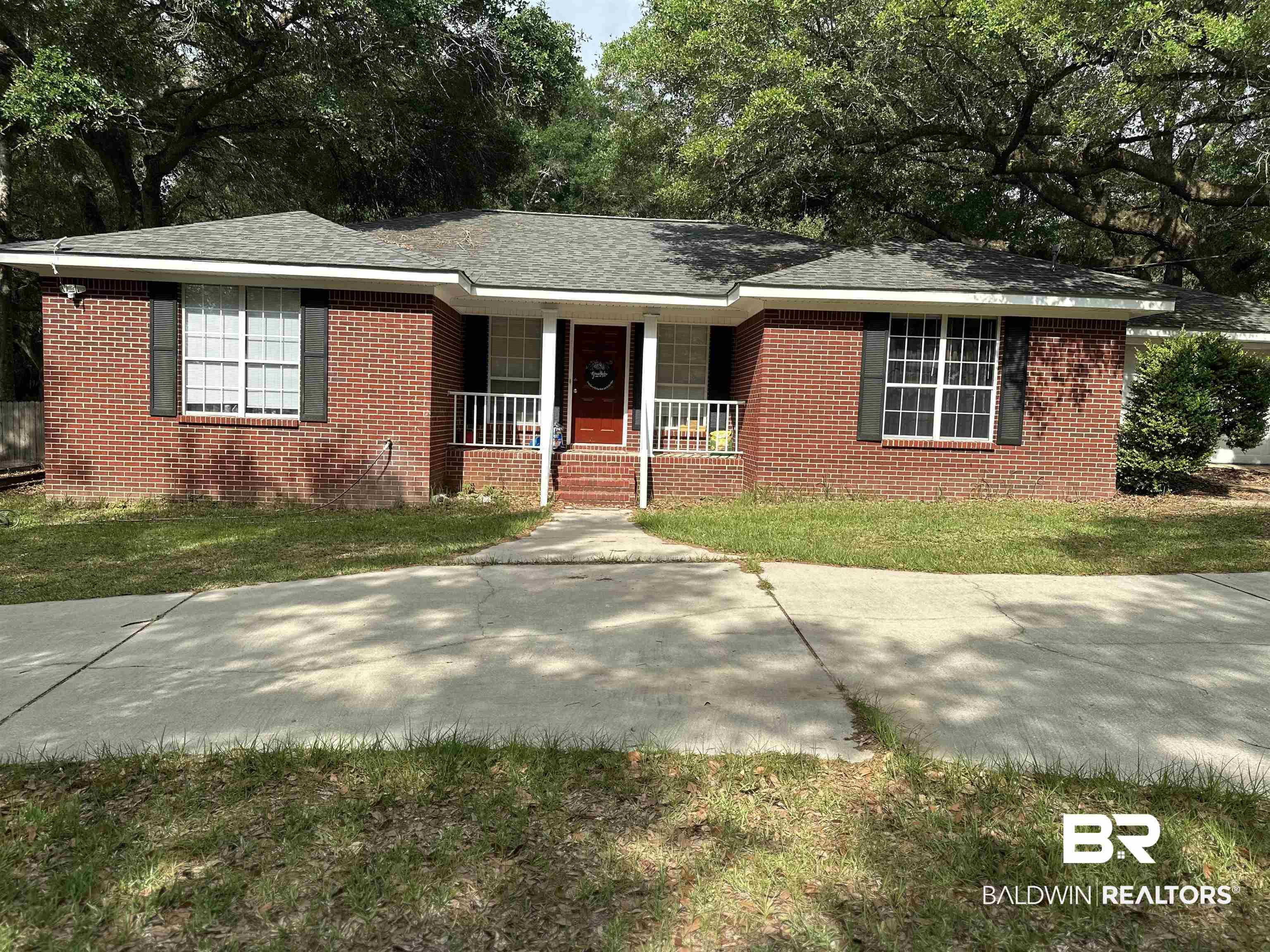 Image 1: Brick exterior with dark shutters, a covered front porch, and a concrete driveway