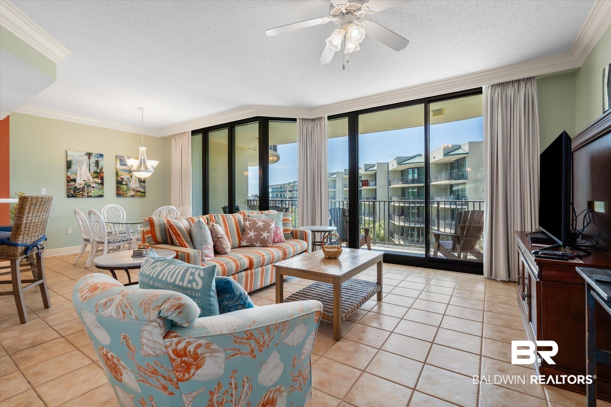 Image 3: Living room featuring light tile patterned floors, a wall of windows, and crown molding