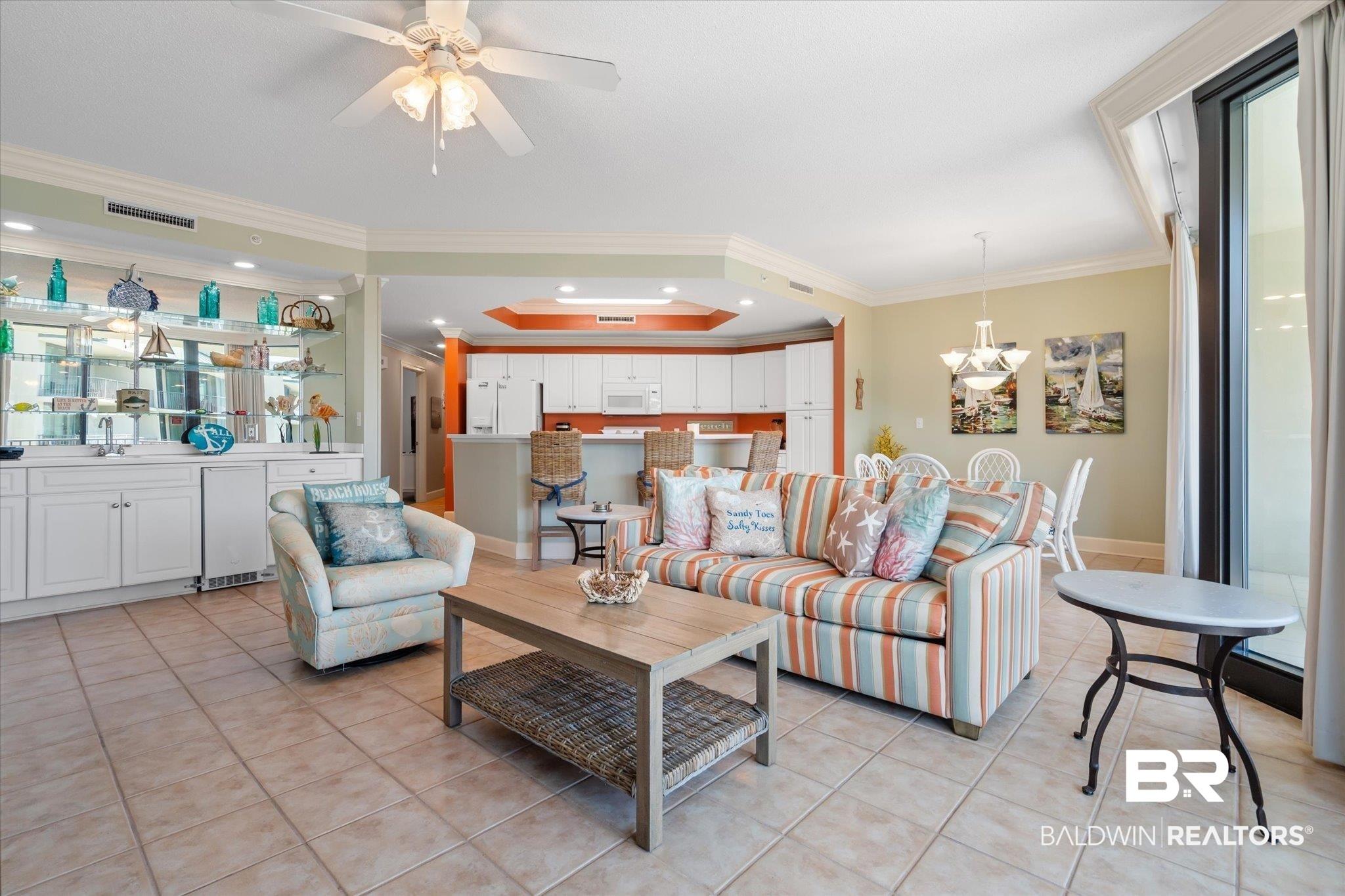 Image 4: Living area with crown molding and light tile patterned floors.