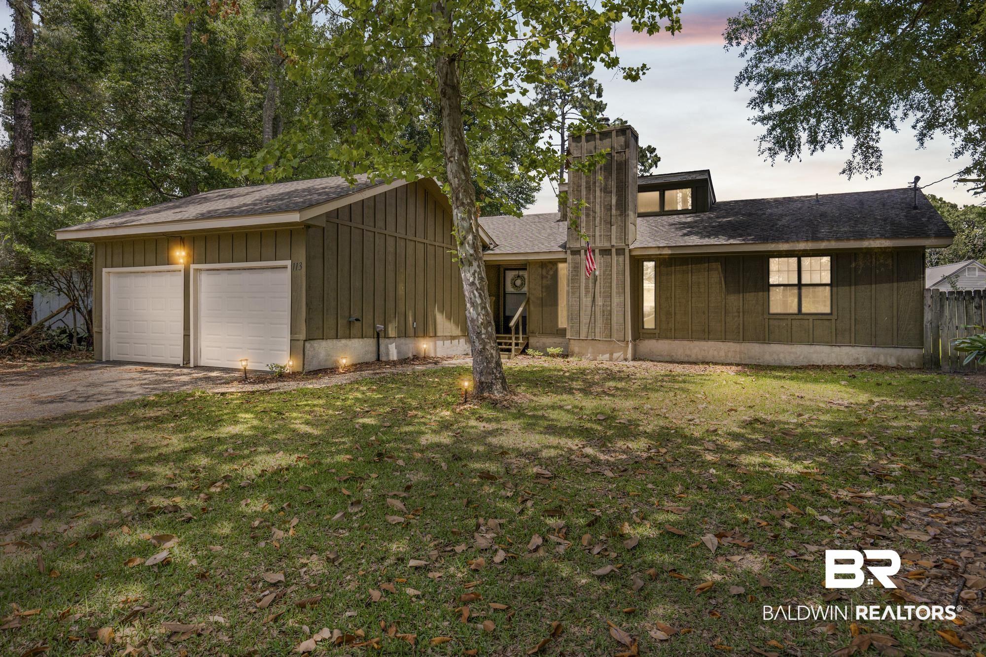 Image 1: Property exterior featuring a two-car garage, board and batten siding, a prominent chimney structure, multiple windows, and exterior lighting
