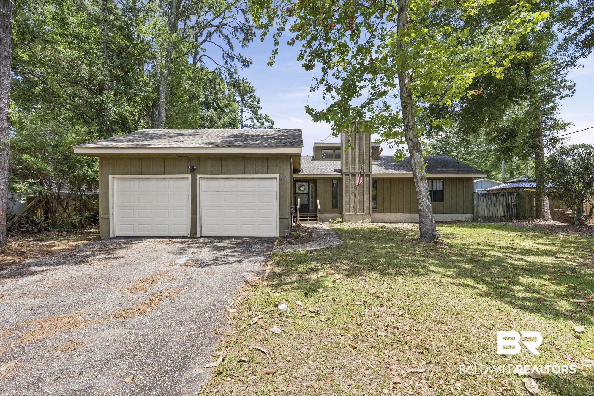 Image 3: Ranch-style exterior with wood siding, a two-car garage with panel doors, a shingle roof, and a mature tree-lined front yard
