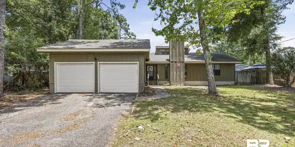Image 3: Ranch-style exterior with wood siding, a two-car garage with panel doors, a shingle roof, and a mature tree-lined front yard