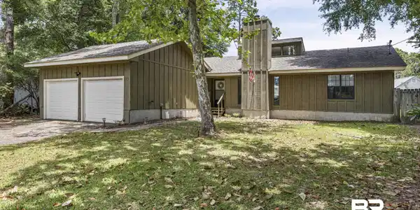 Image 4: Exterior featuring board and batten siding, a prominent chimney structure, a two-car garage with white doors, a front entry with steps, and a shingle roof