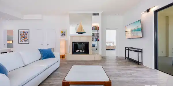 Image 4: Living area featuring light wood-finish flooring and a fireplace with a stone surround