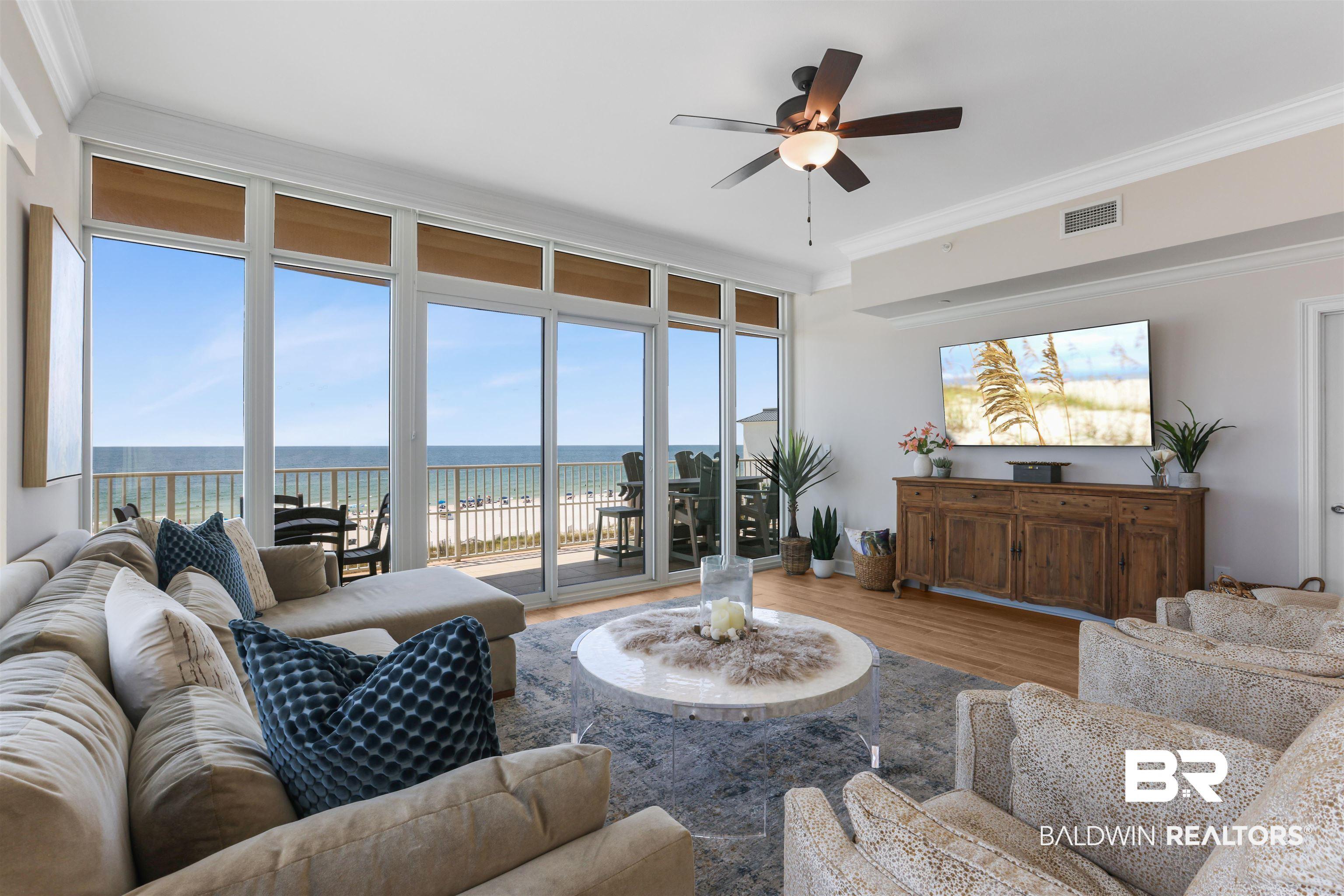 Image 3: Living room with ceiling fan, wood finished floors, ornamental molding, and expansive windows