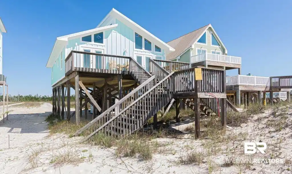 Image 1: Elevated coastal property featuring a turquoise exterior with white trim