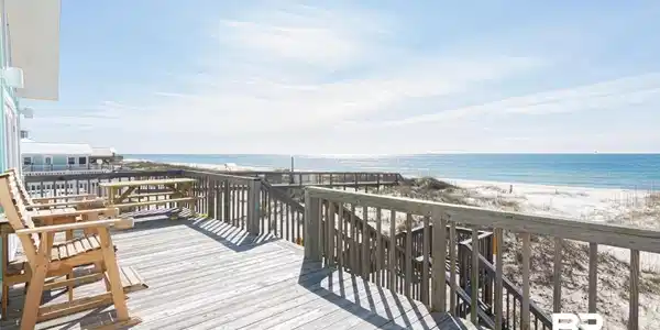 Image 3: Spacious outdoor deck with natural wood flooring and railing, featuring direct access to a white sand beach and expansive ocean