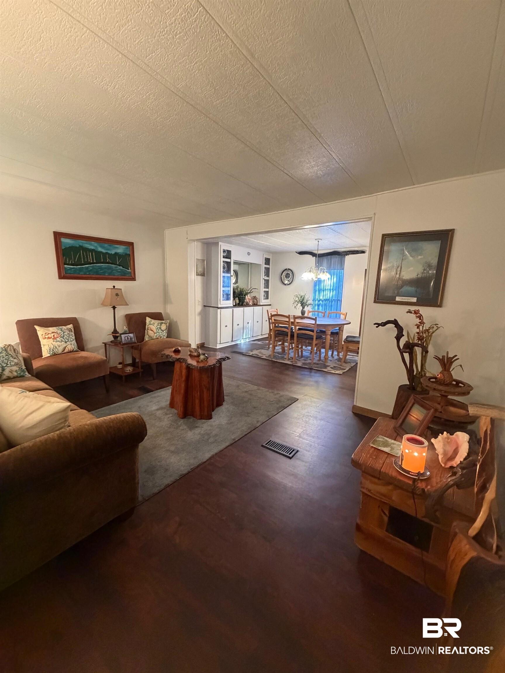 Image 4: Living area featuring dark wood finished floors and a textured ceiling
