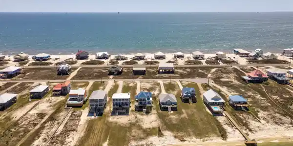 Image 3: Aerial view of property's location with waterfront with a beach and nearby suburban area