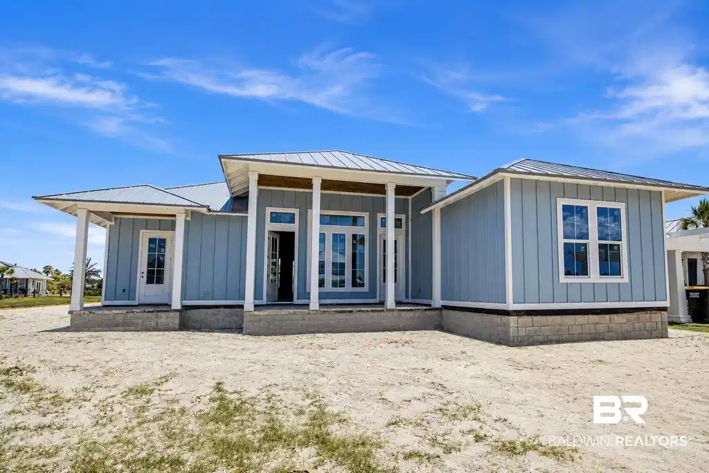 Image 1: Light blue siding exterior featuring a multi-gable metal roof and prominent white trim