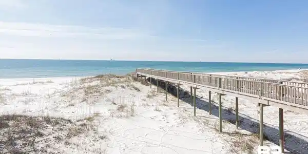 Image 4: Expansive sandy beach with a prominent boardwalk, featuring light-colored sand and dune grasses