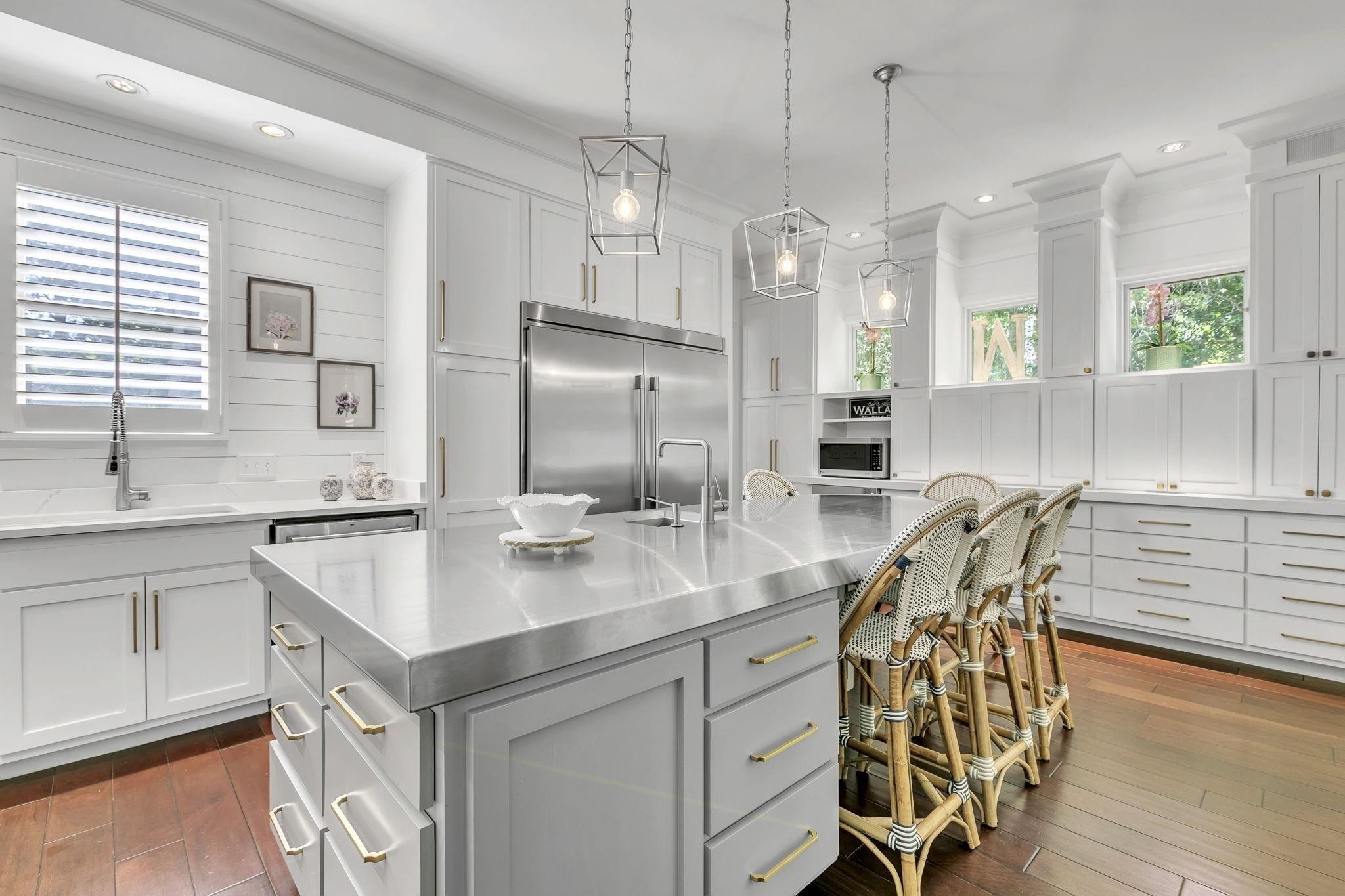 Image 3: Kitchen featuring stainless steel built in fridge, a sink, dark wood finished floors, stainless steel countertops, and hanging light fixtures