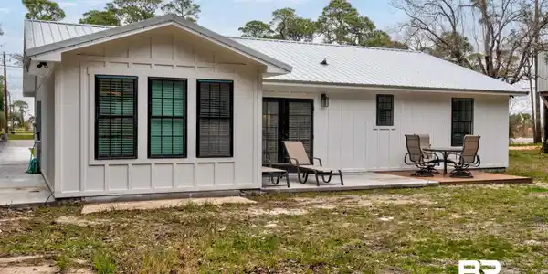 Image 2: Back of house with a metal roof, board and batten siding, and a patio