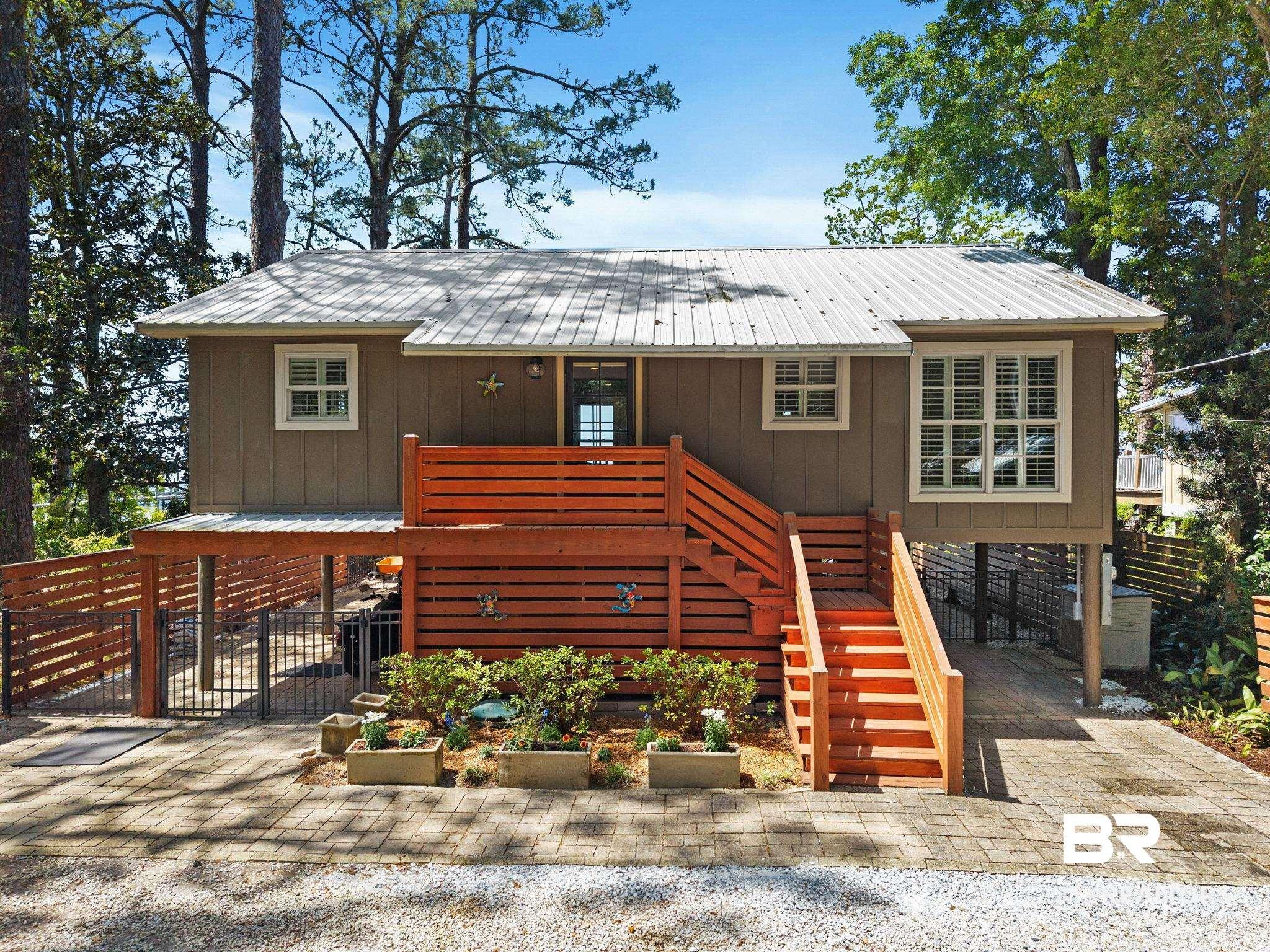 Image 3: View from Scenic 98 with a metal roof, board and batten siding, and parking underneath.