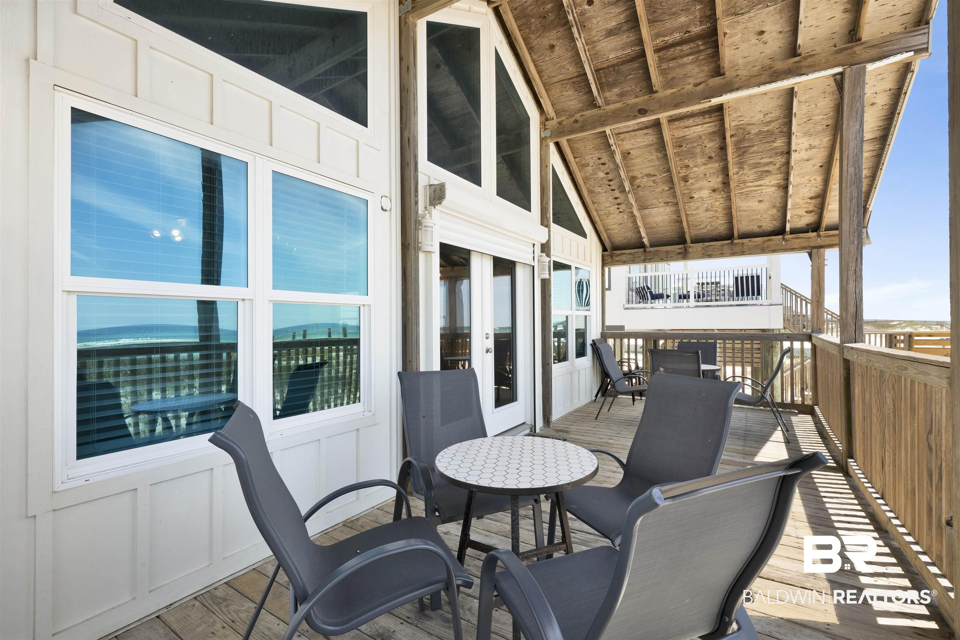 Image 3: Expansive covered deck featuring natural wood flooring and railing