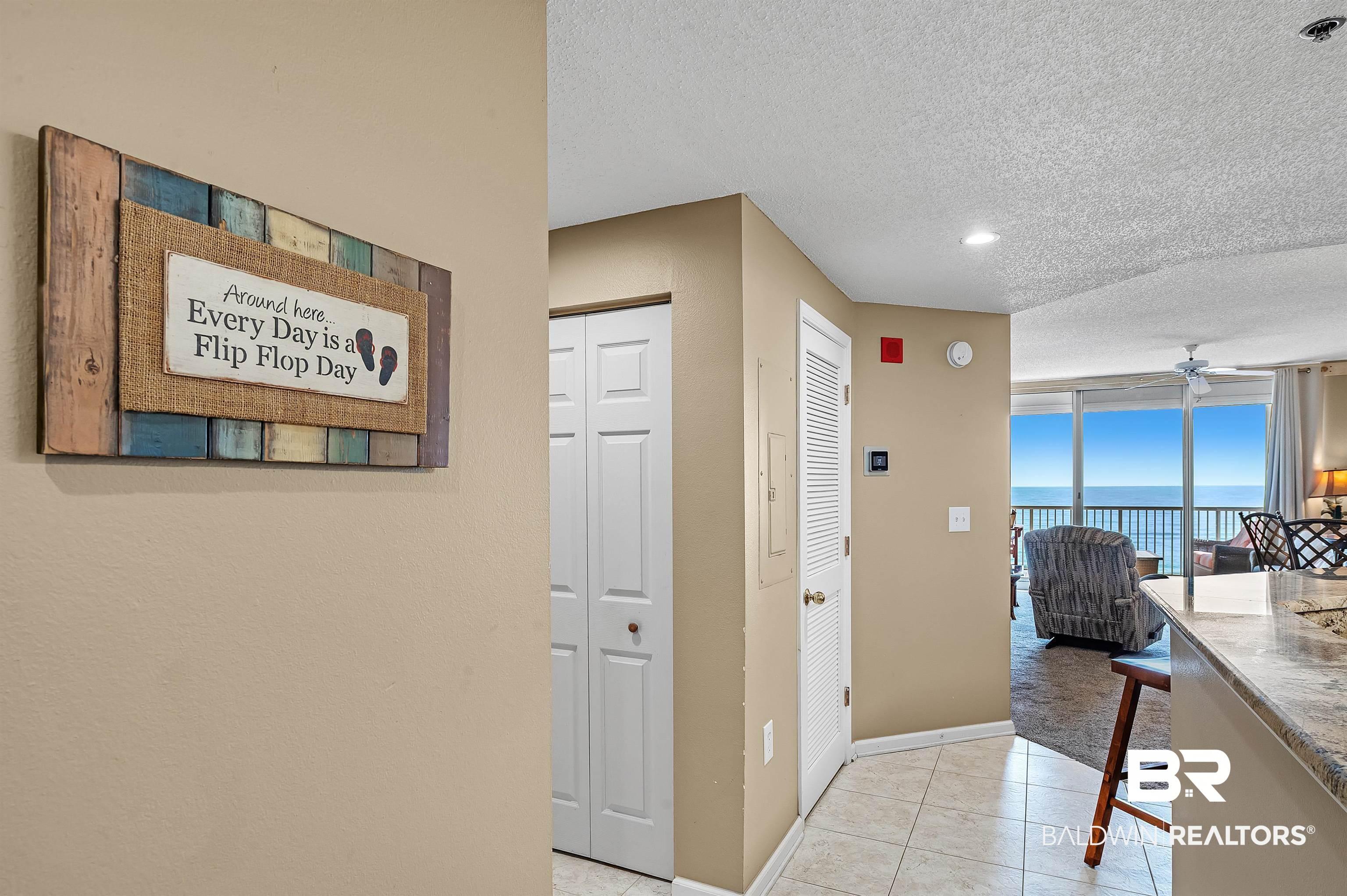 Image 2: Hallway featuring light tile patterned floors, baseboards, a water view, and a textured ceiling