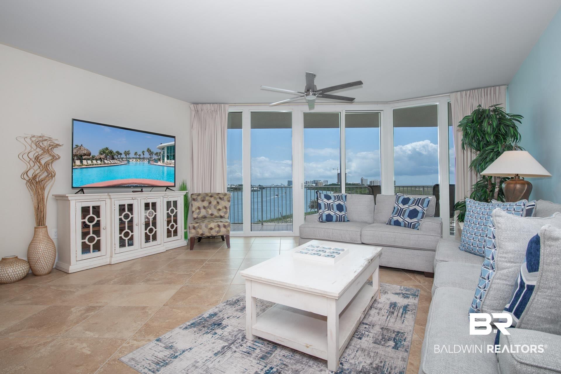 Image 2: Living area with a wall of windows and a ceiling fan