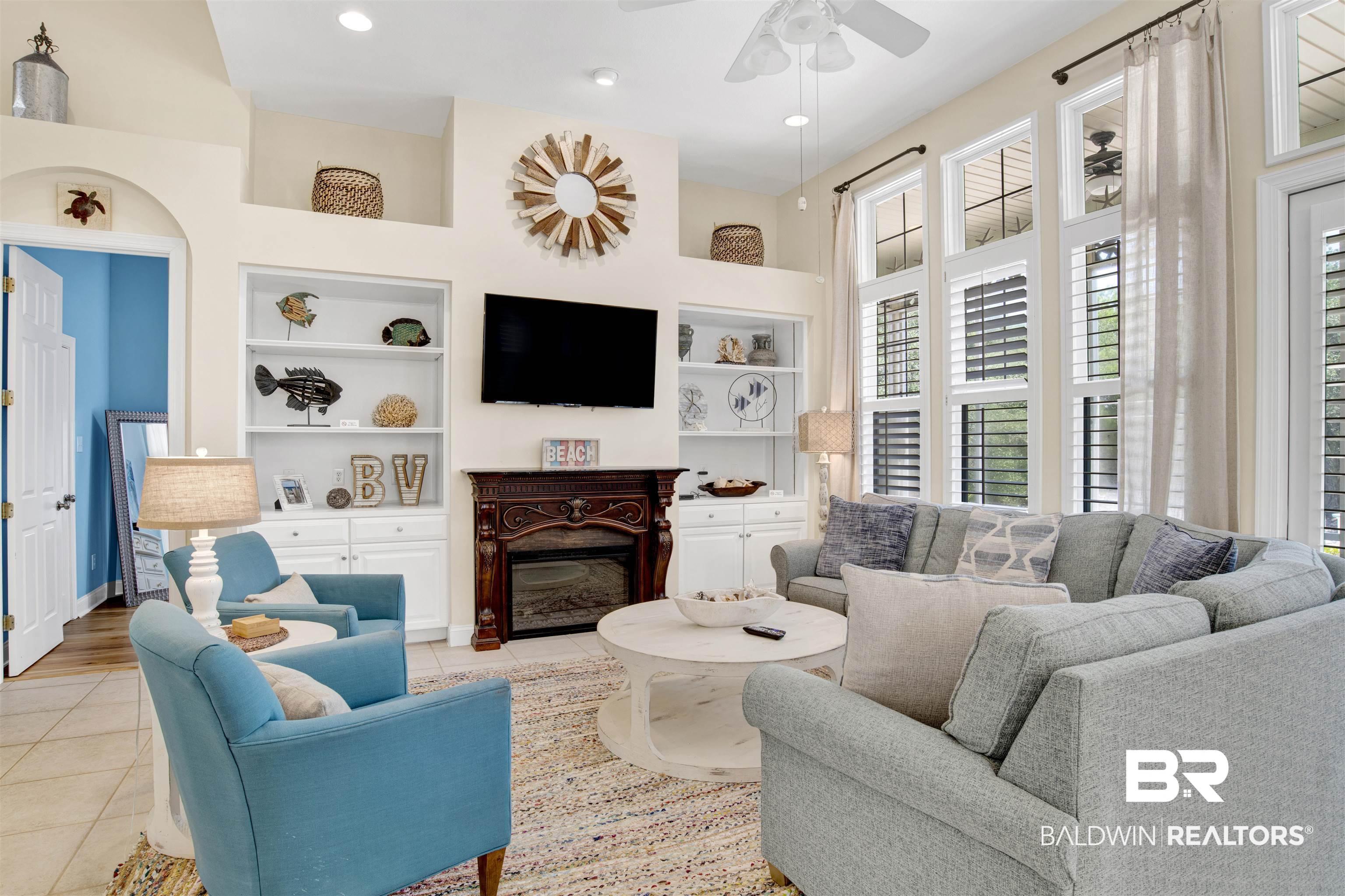 Image 4: Living room with built in shelves, light tile patterned flooring, a glass covered fireplace, recessed lighting, and a ceiling fan
