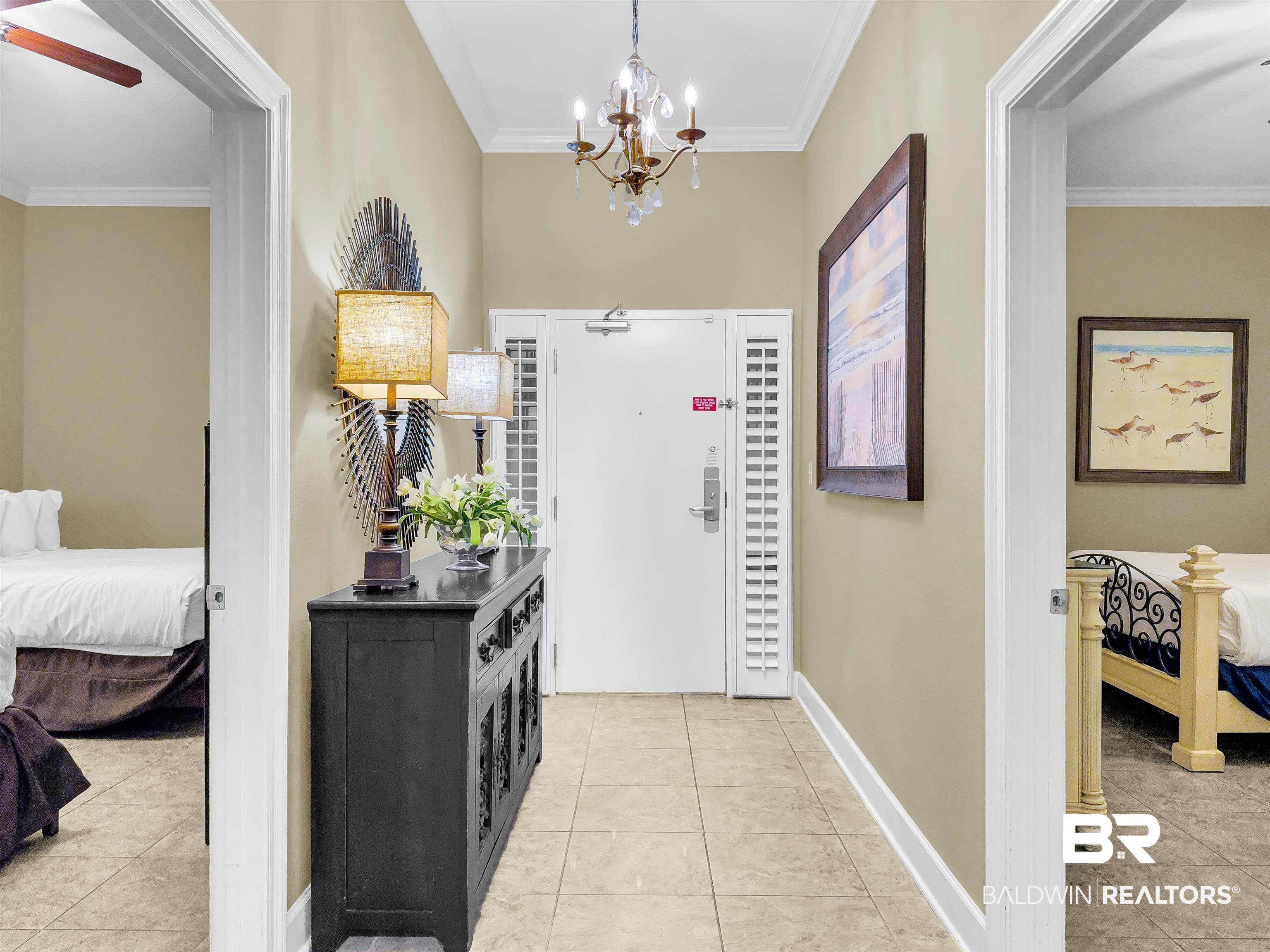 Image 3: Foyer entrance with crown molding, light tile patterned floors, and a chandelier