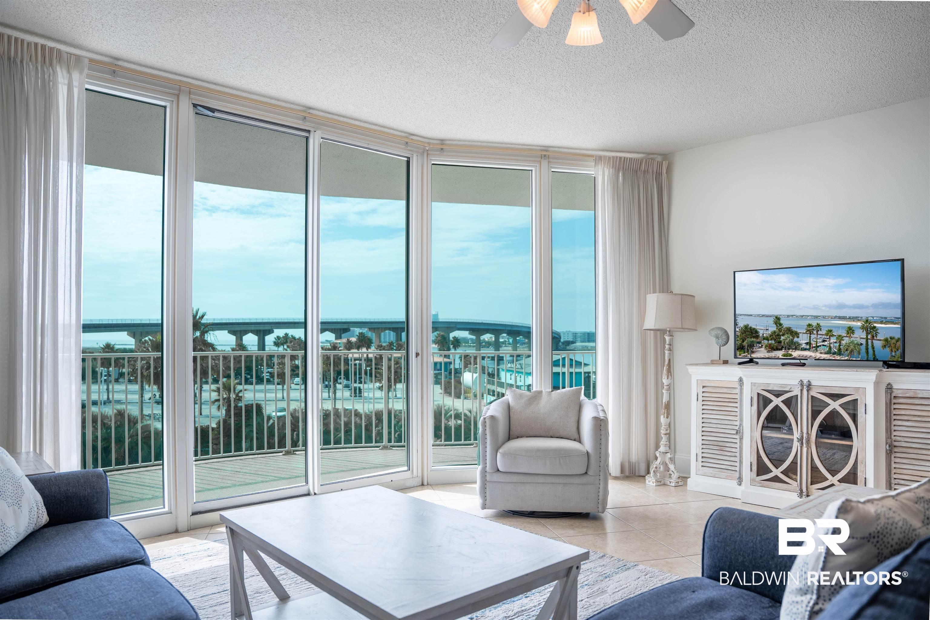 Image 2: Living room featuring expansive windows, a textured ceiling, healthy amount of natural light, a water view, and ceiling fan