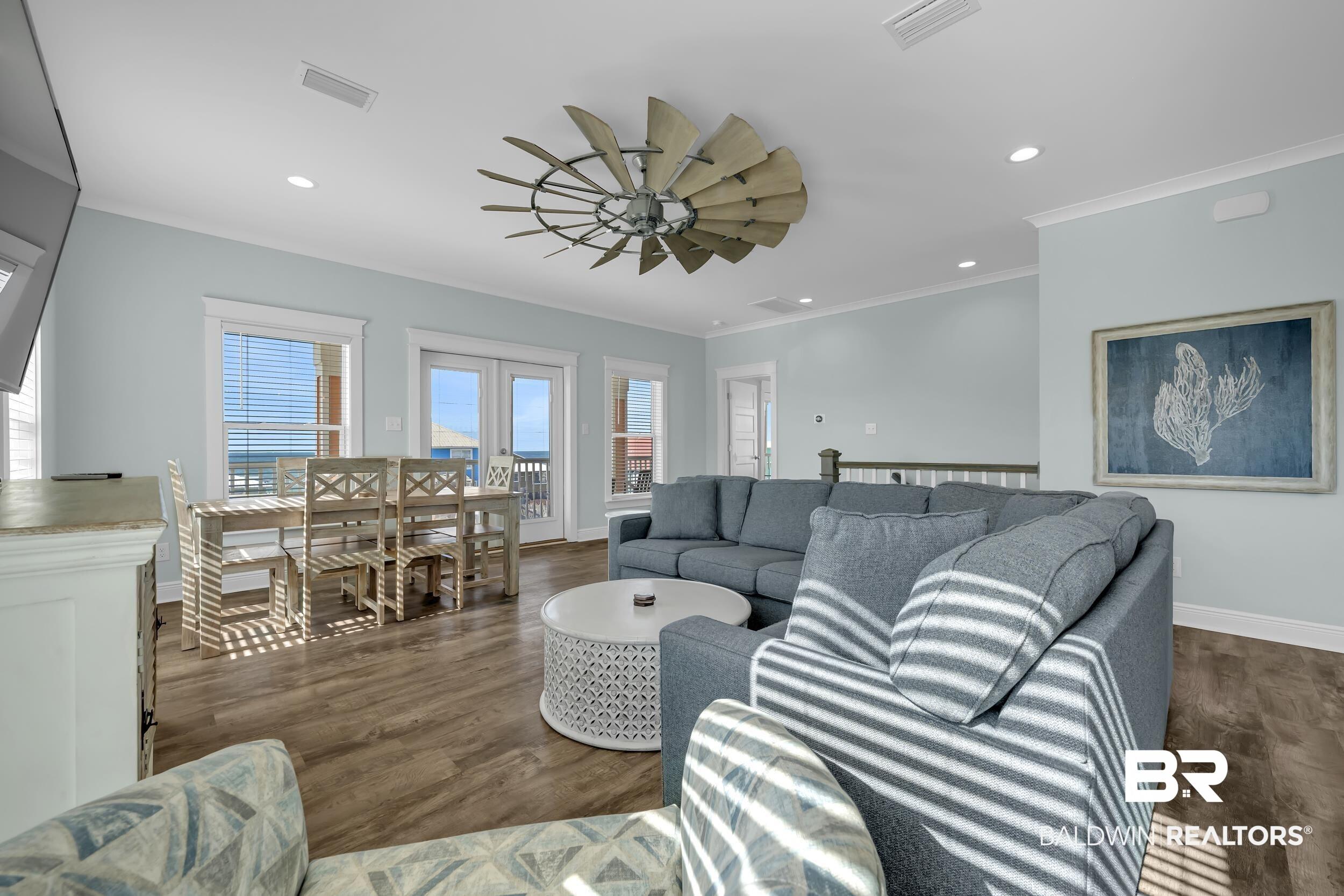 Image 2: Open-concept living area featuring wood-finish flooring, a unique ceiling fan, recessed lighting, and crown molding