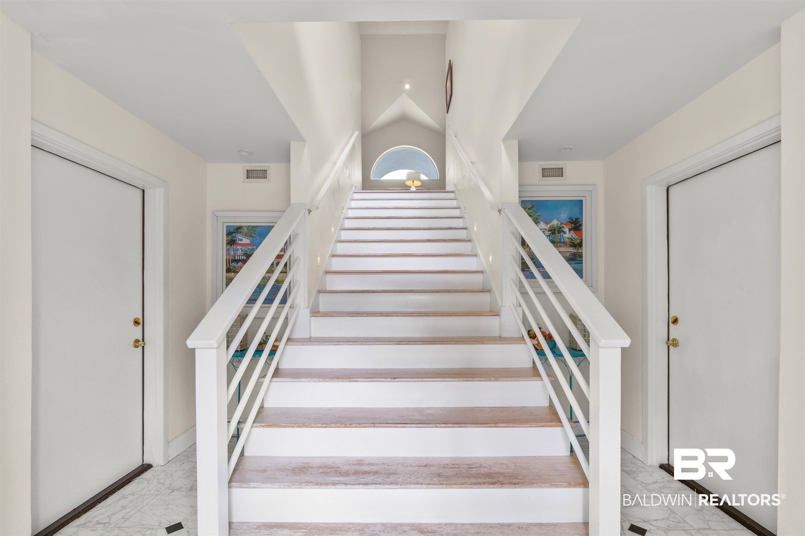 Image 4: Stairway featuring marble finish floors. Side doors into both Garage Areas