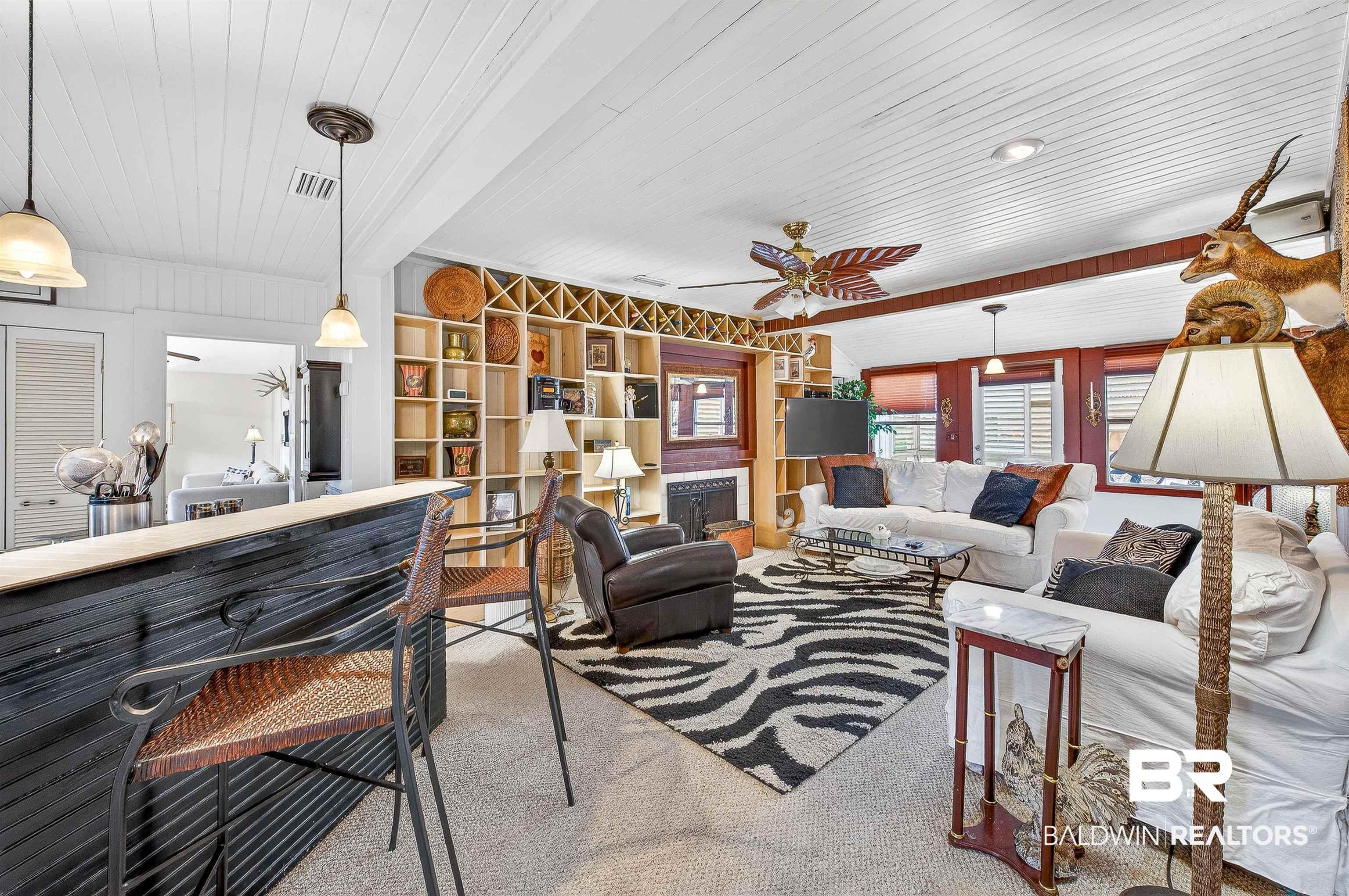 Image 4: Living area featuring a fireplace, ceiling fan, wood ceiling, and carpet flooring
