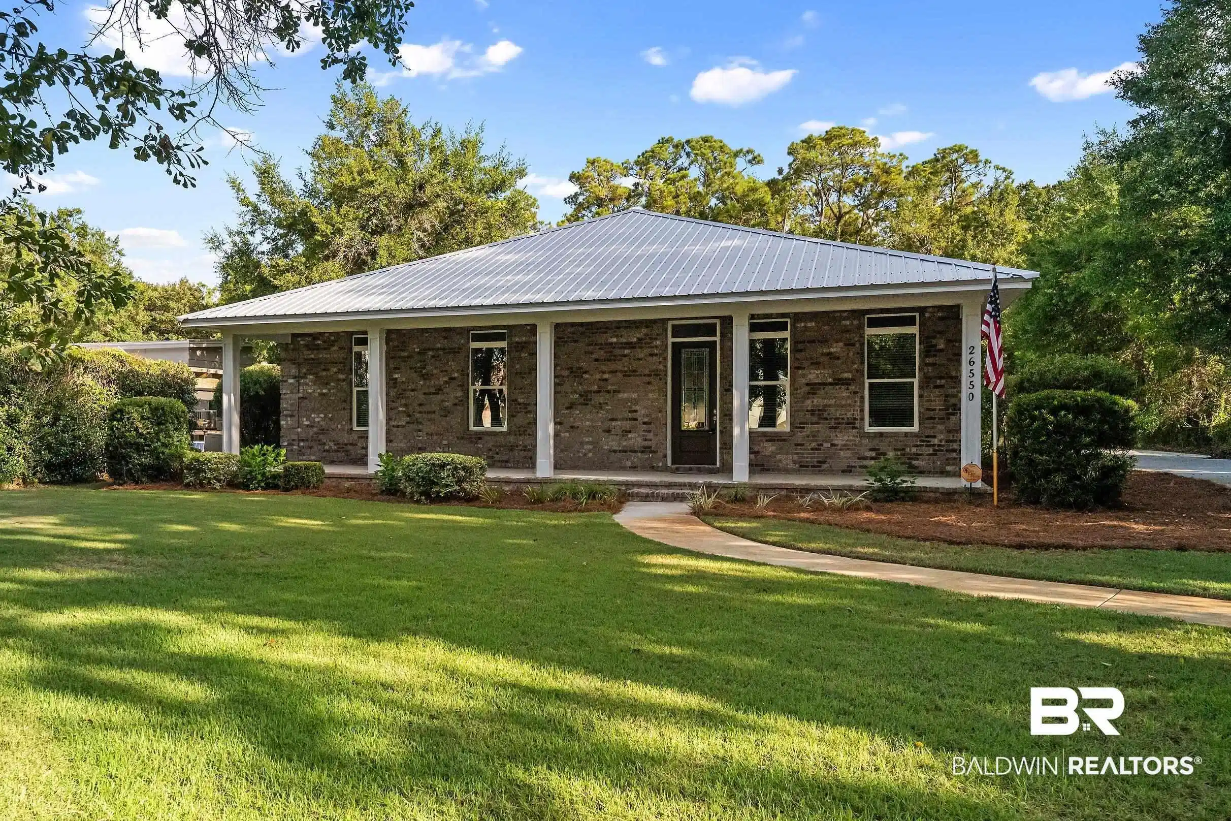 Image 1: Exterior featuring a metal roof, brick facade, covered front porch, and a curved walkway
