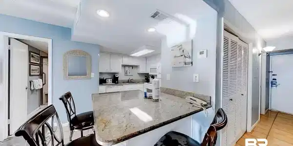 Image 2: Kitchen with white cabinetry, kitchen peninsula, dark stone countertops, and a kitchen bar