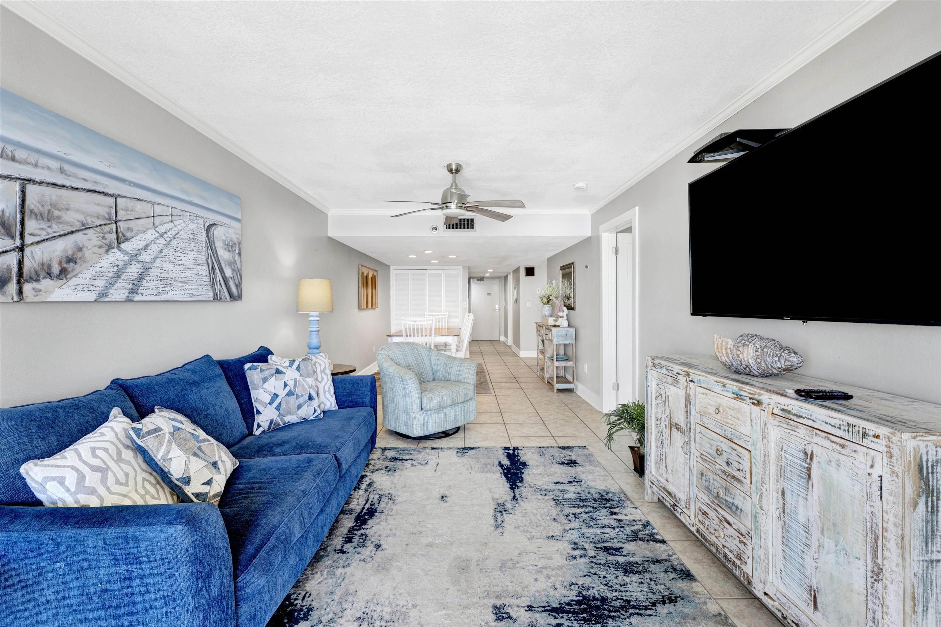 Image 3: Living area with crown molding, light tile patterned floors, and ceiling fan
