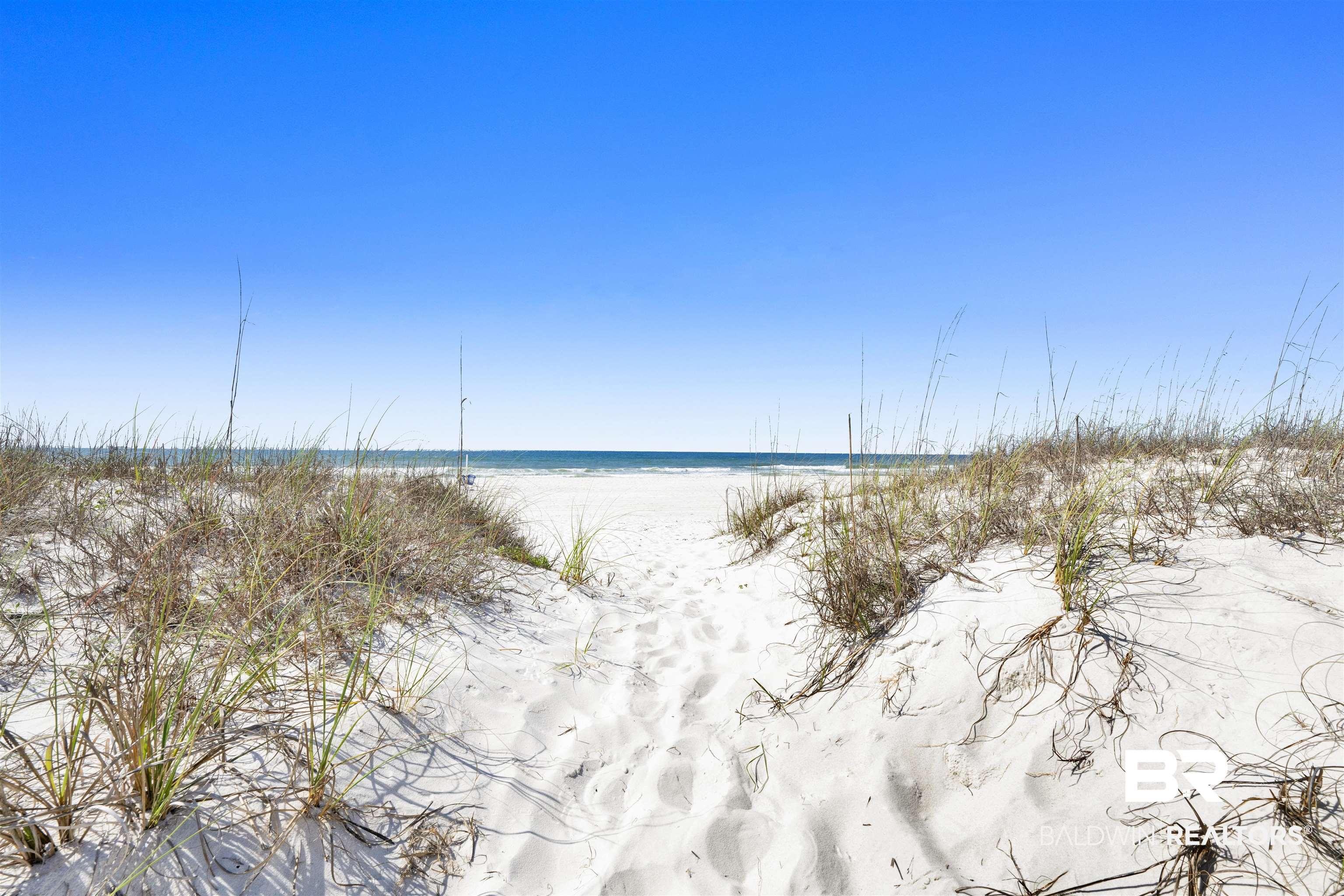 Image 2: White sand beach with a clear blue sky and ocean horizon