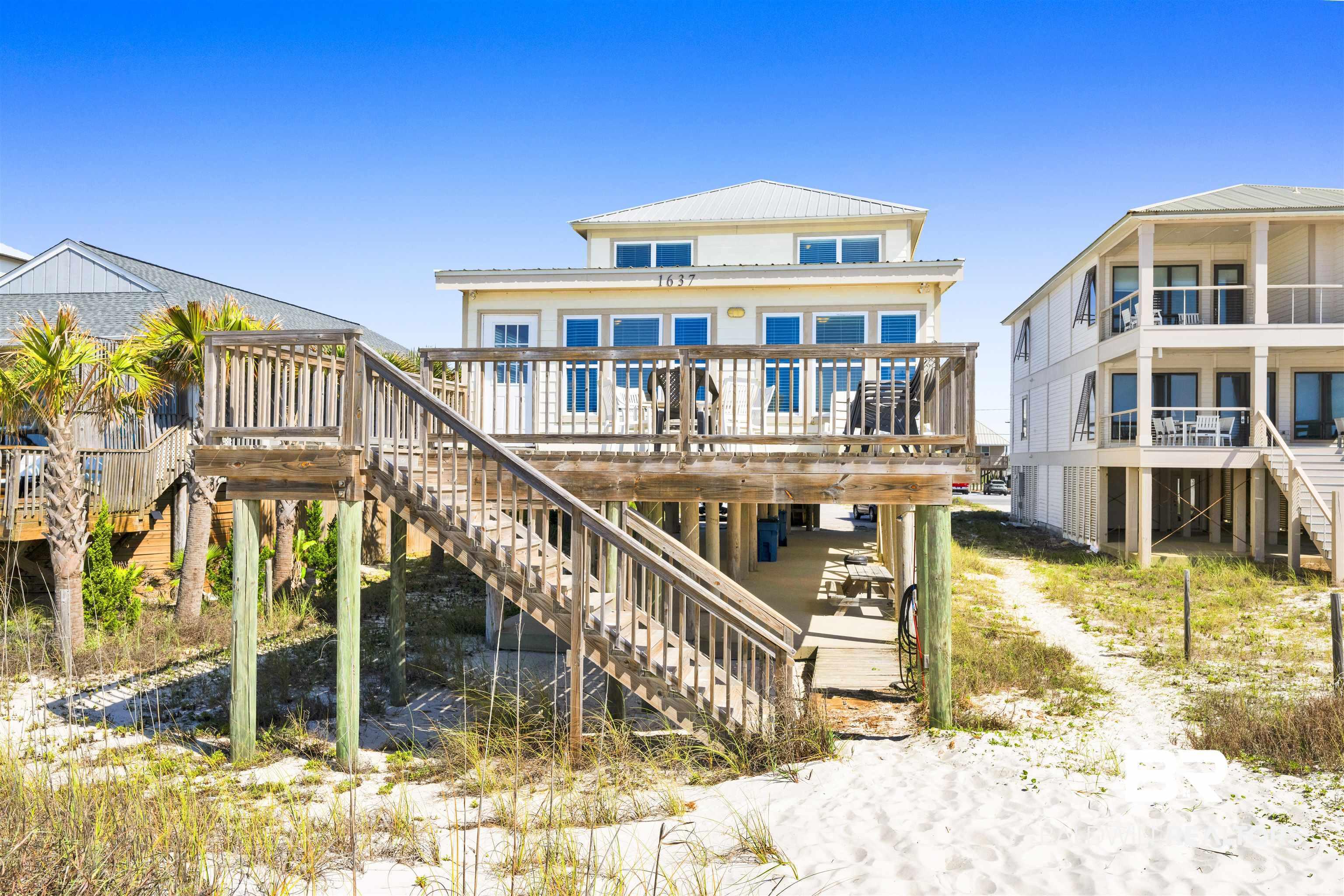 Image 3: Elevated coastal residence featuring a sand-colored exterior, multiple balconies, and a metal roof