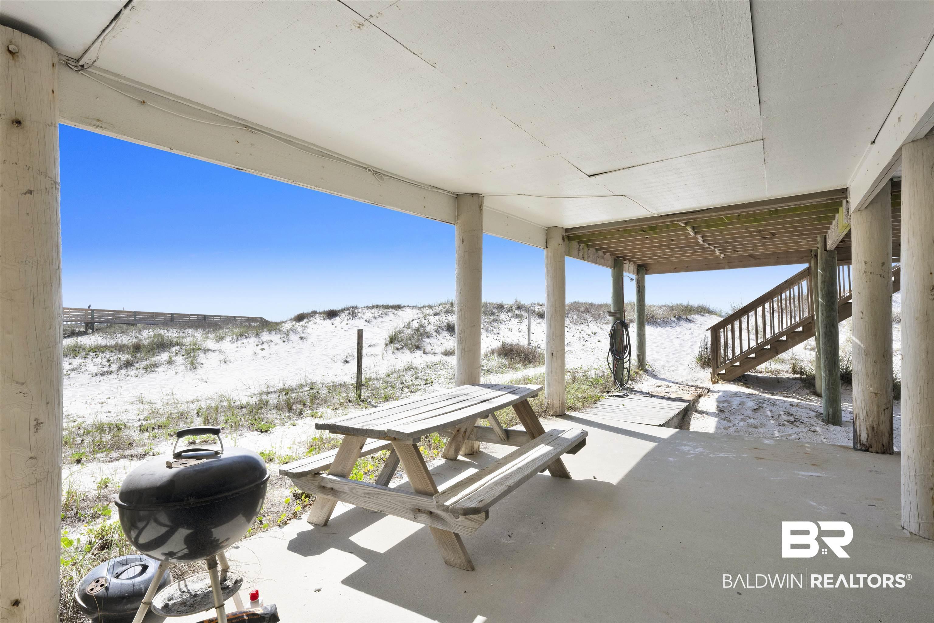 Image 4: Ground-level covered patio featuring a concrete slab, supporting columns, and an open-air setting