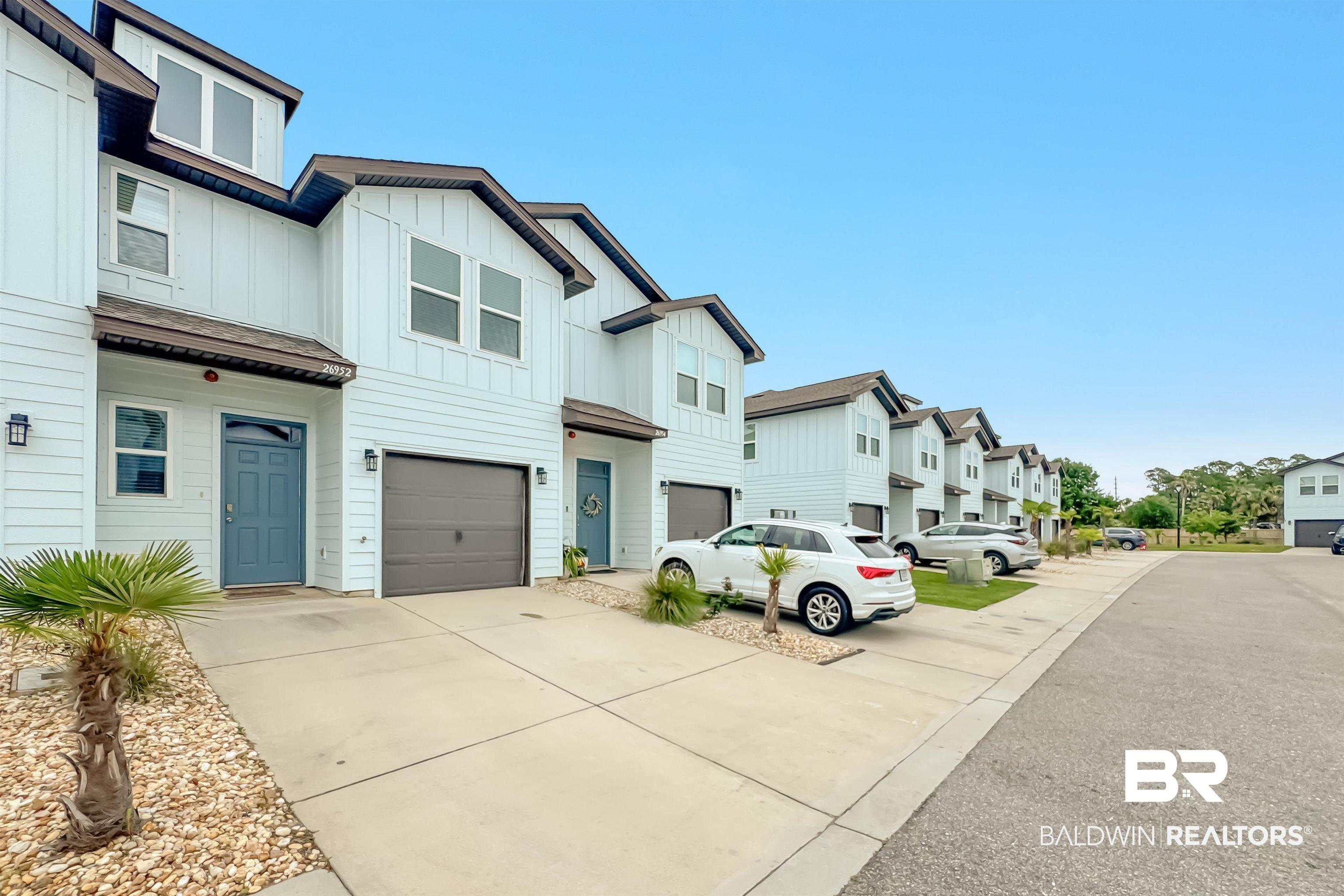 Image 3: Modern townhome-style residences featuring light-colored siding, a dark-toned roofline, and attached garages