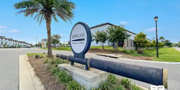 Image 4: Community entrance signage featuring a decorative cannon and a palm tree, with paved roadways, maintained landscaping, and multi-story structures in the background