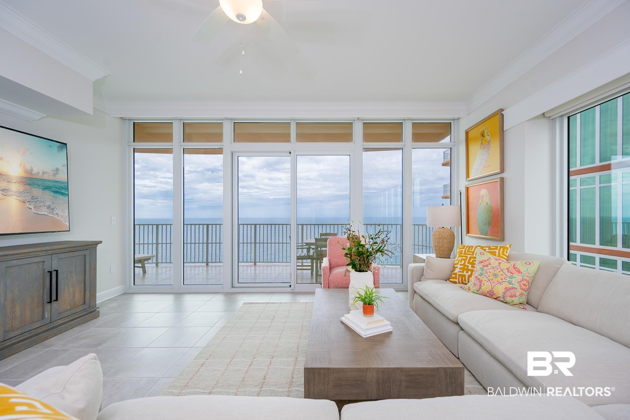 Image 2: Floor-to-ceiling glass doors open to a balcony with metal railings and water