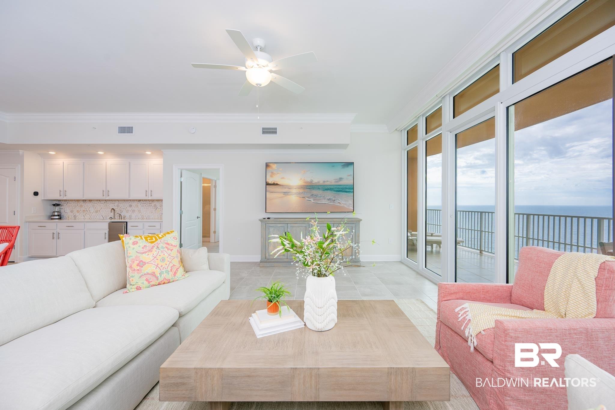 Image 3: Open concept living area with large format tile flooring and a wet bar featuring white cabinetry and a tile backsplash